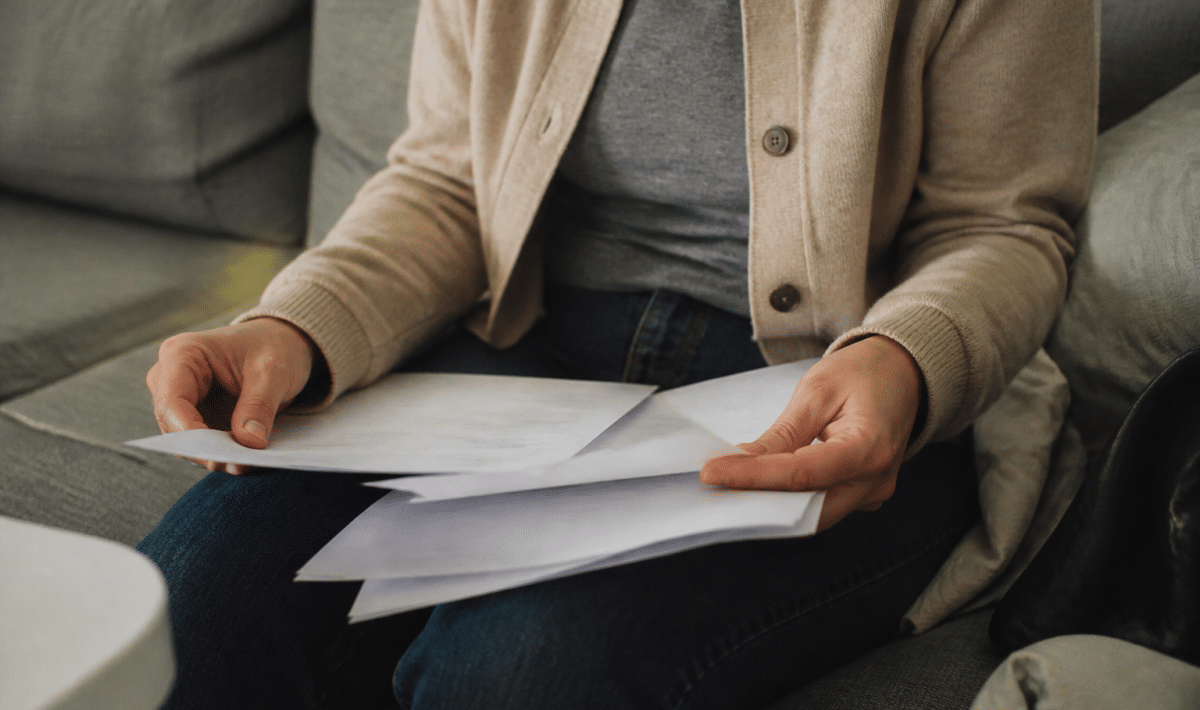 Personne assise tenant documents pret bancaire et certificat maladie
