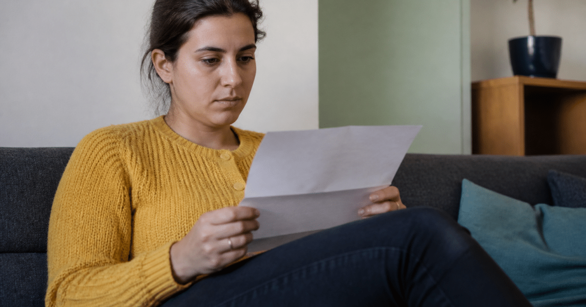 personne assise tenant document pret immobilier entre mains