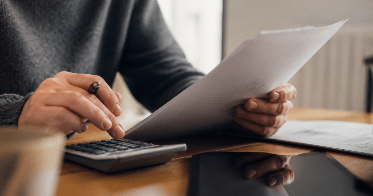 Personne tenant document pret immobilier avec calculatrice et stylo