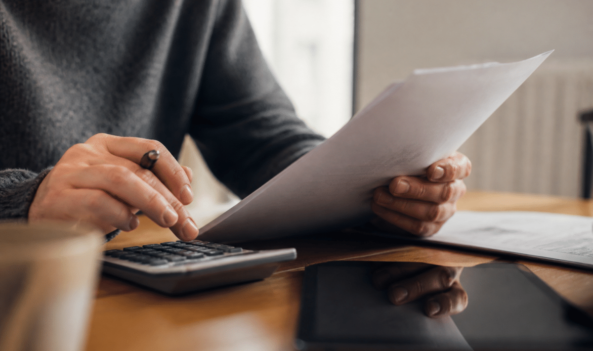 Personne tenant document pret immobilier avec calculatrice et stylo