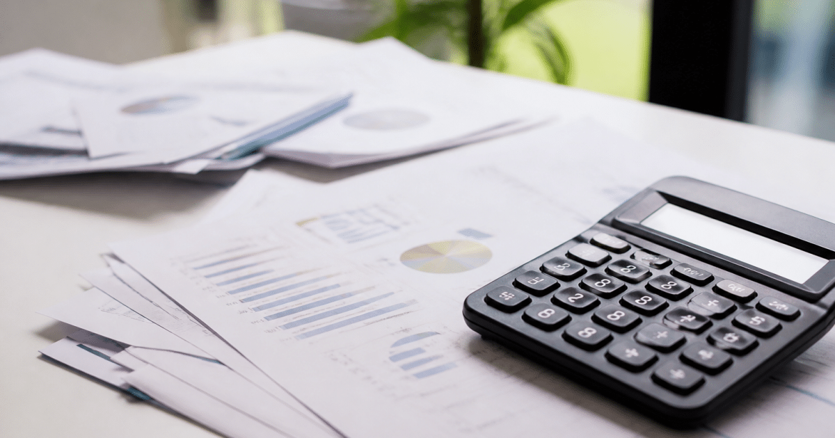 Documents financiers et calculatrice poses sur bureau blanc