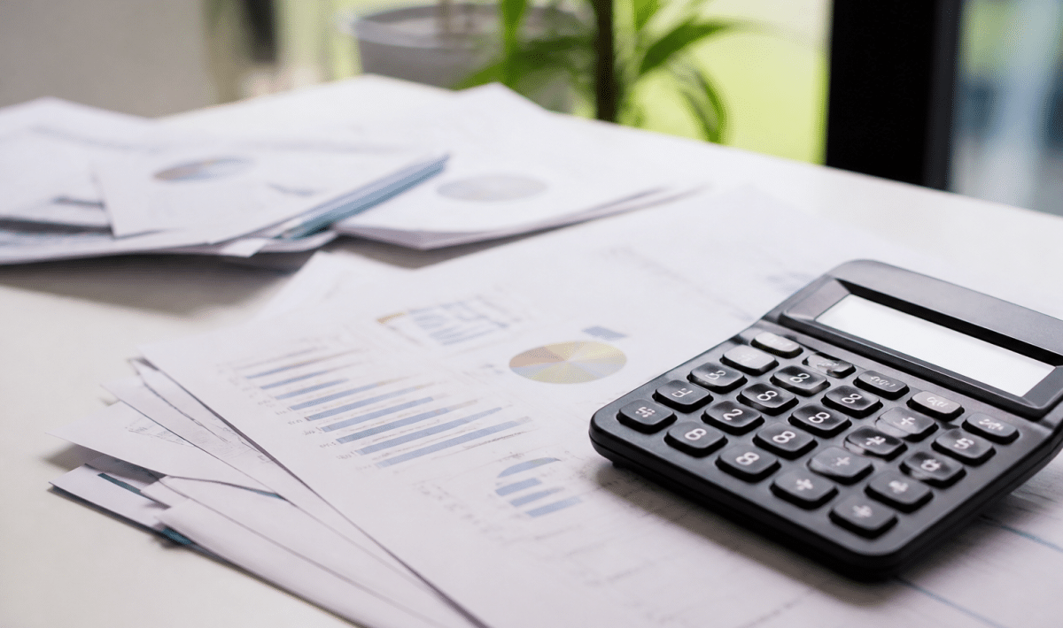 Documents financiers et calculatrice poses sur bureau blanc