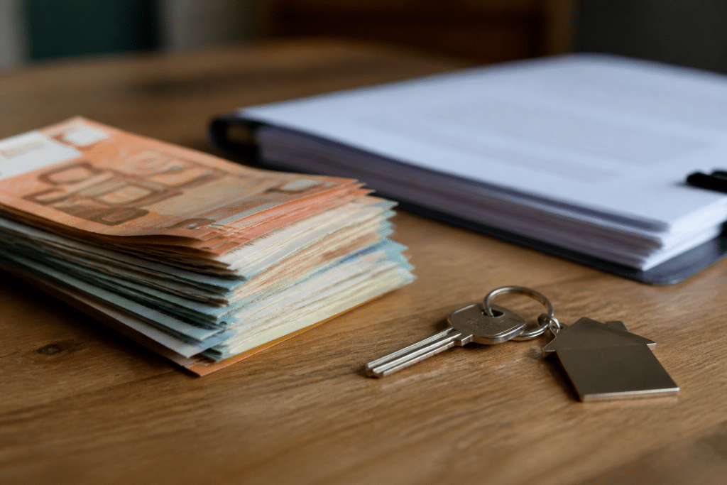 Pile de billets aupres d'une cle et documents immobiliers