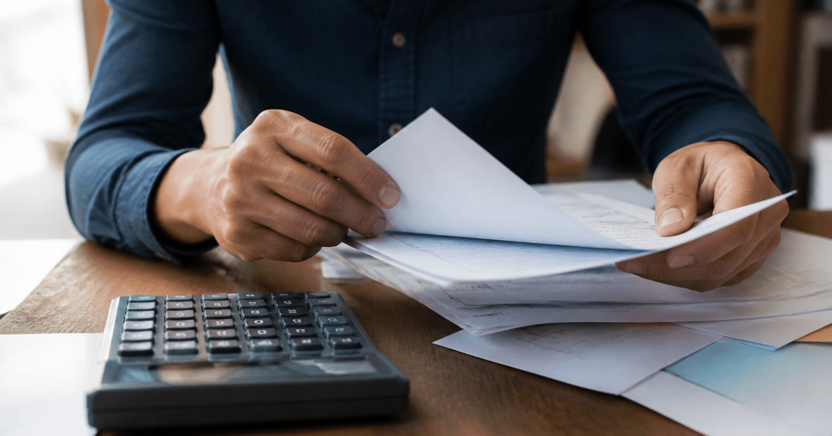 Mains tenant documents financiers sur bureau avec calculatrice
