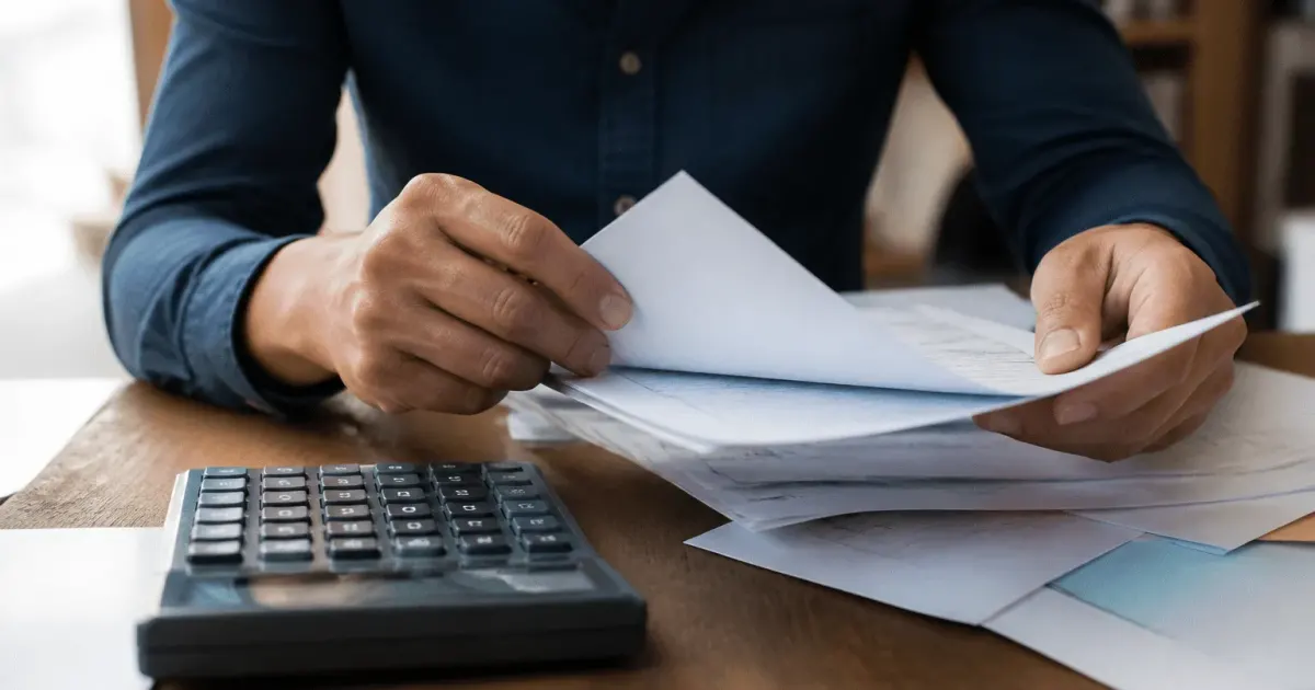 Mains tenant documents financiers sur bureau avec calculatrice