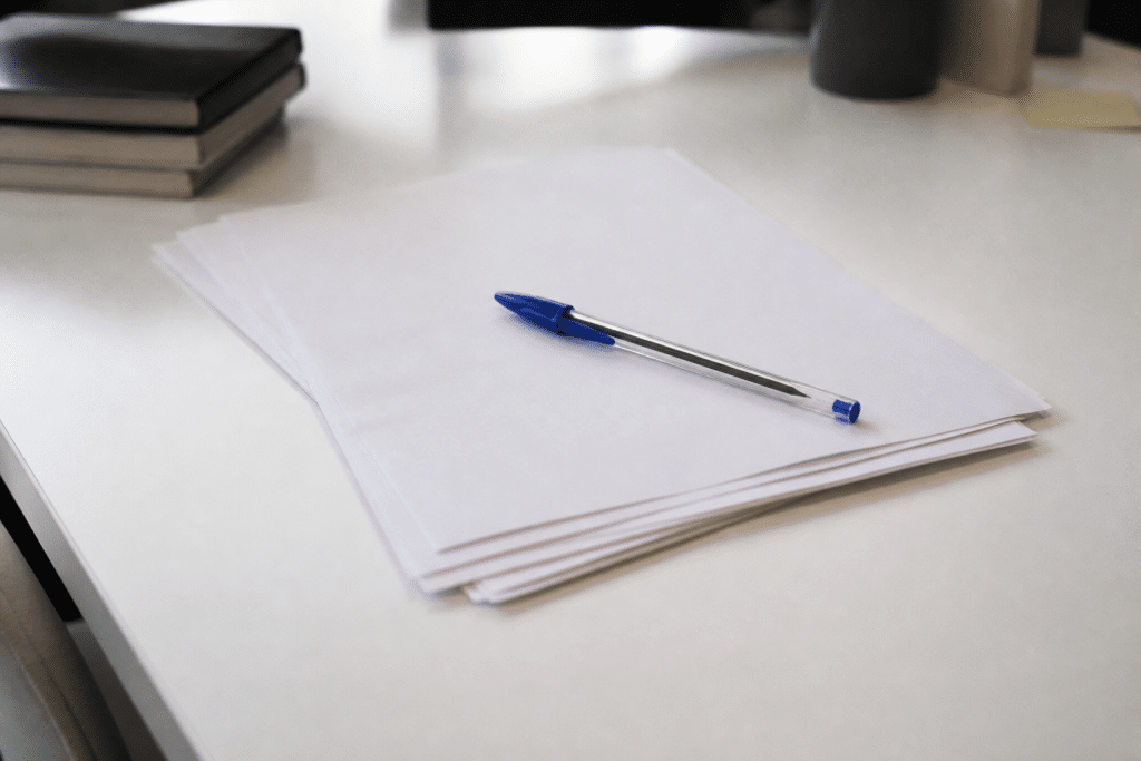 Documents papier avec stylo bleu sur bureau blanc