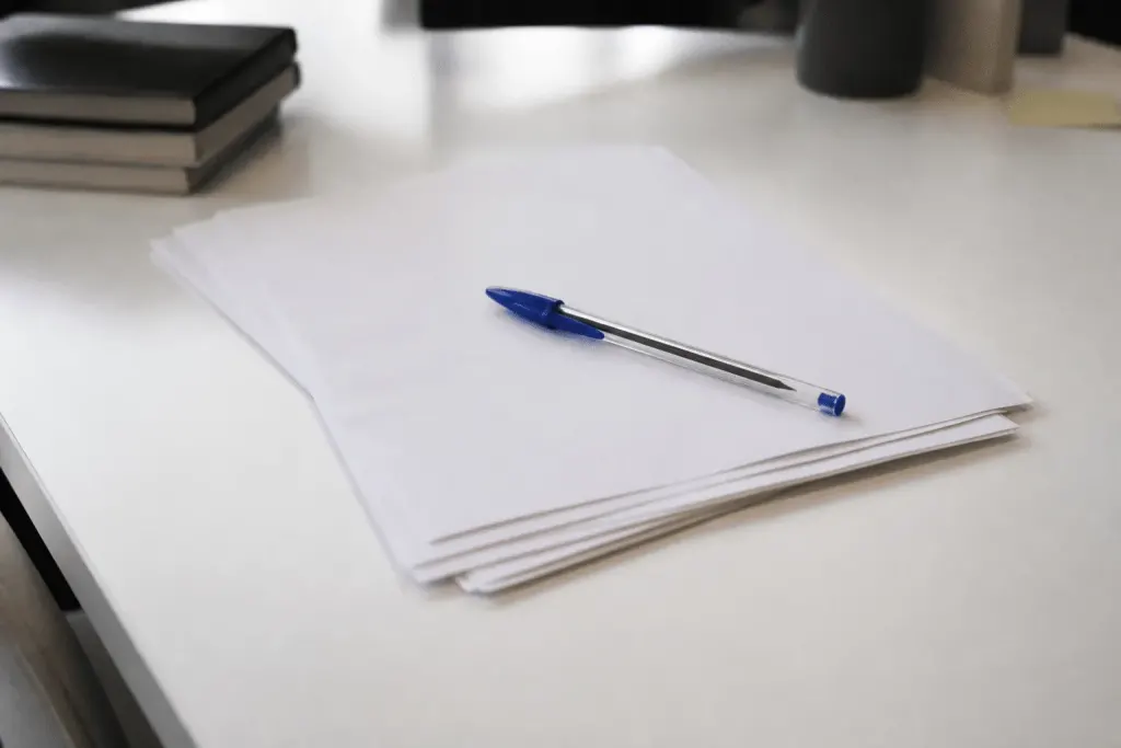 Documents papier avec stylo bleu sur bureau blanc