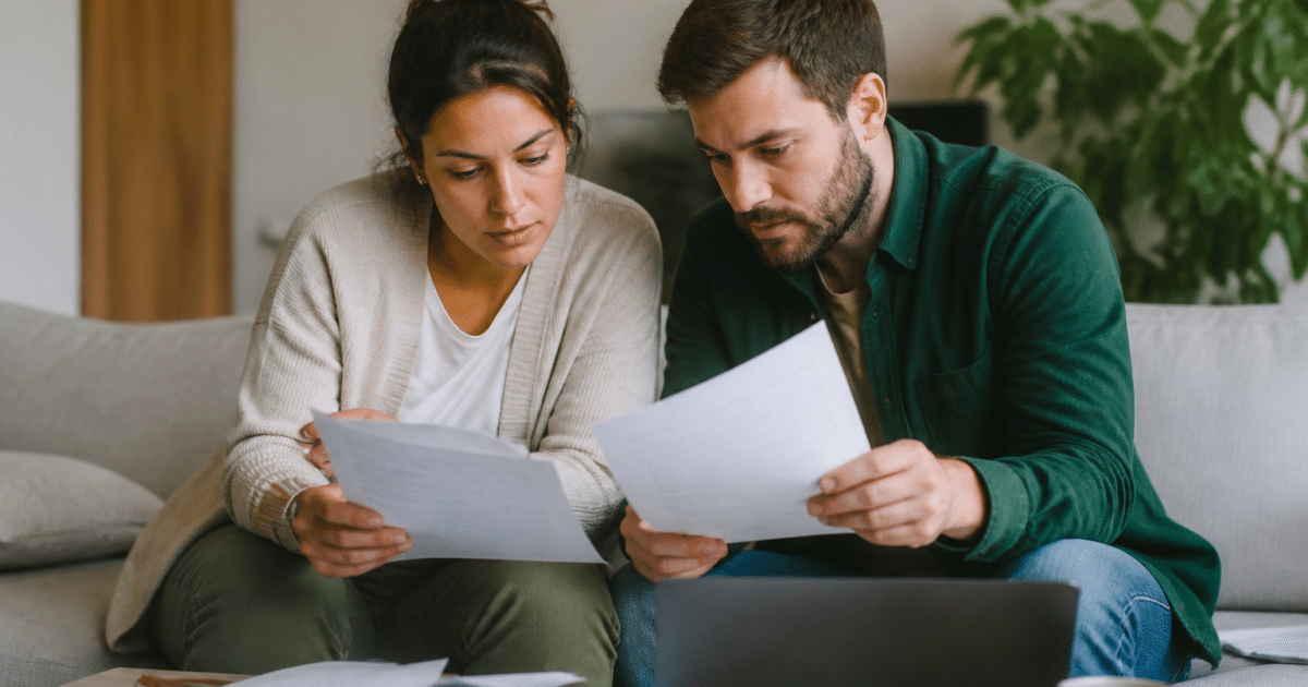 Couple assis examinant documents pret bancaire ensemble