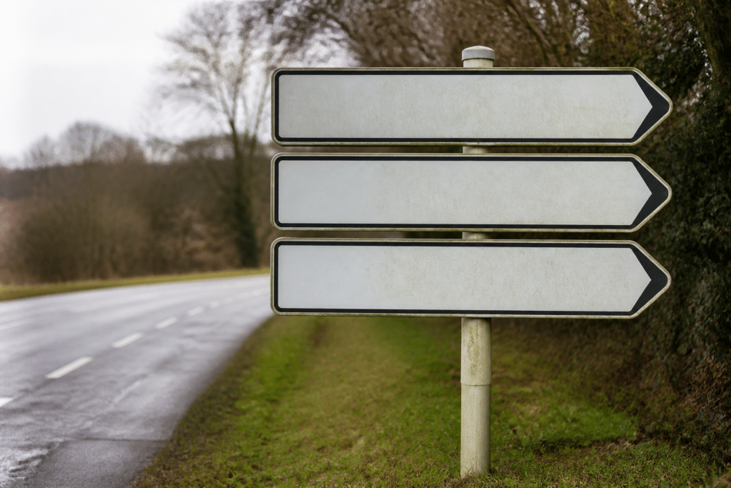 Trois panneaux directionnels indiquant villes voisines avec prix immobiliers