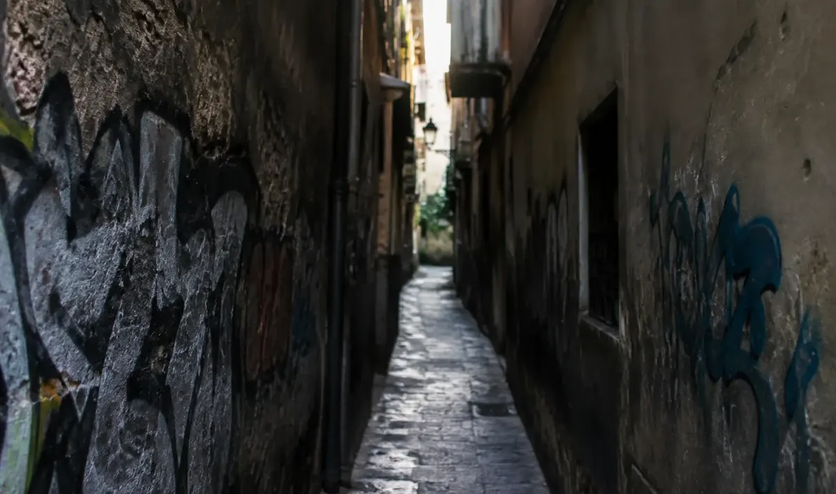 Rue etroite sombre avec murs degrades et graffitis